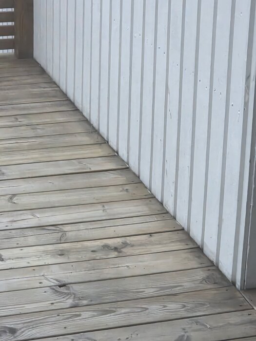 Träaltan med ljusa plankor mot vit träpanelvägg.