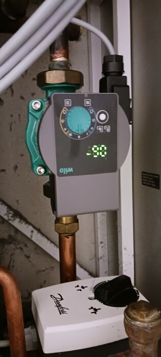 Cirkulationspump installerad på rörsystem, visar temperatur och kontrollpanel.
