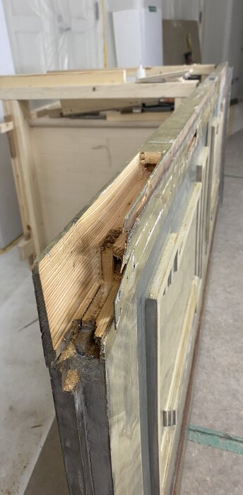 Närbild på en dörrkarm med skador i träet, som visar behov av renovering av de strukturella delarna.
