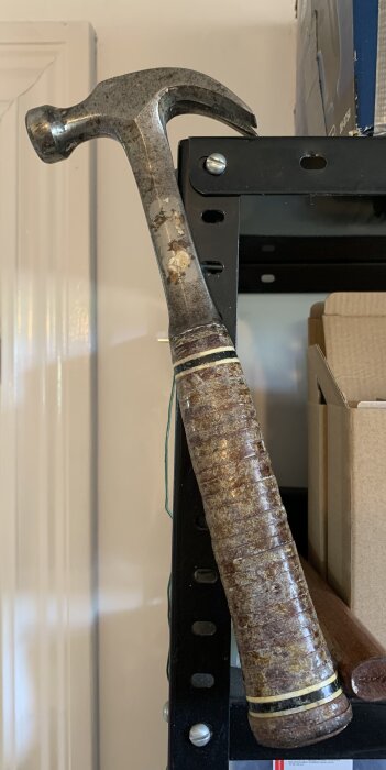 En vintage Estwing Rockford II hammare på en hylla, med slitet handtag och stålhuvud. 16 oz vikt, använd men fortfarande funktionell.