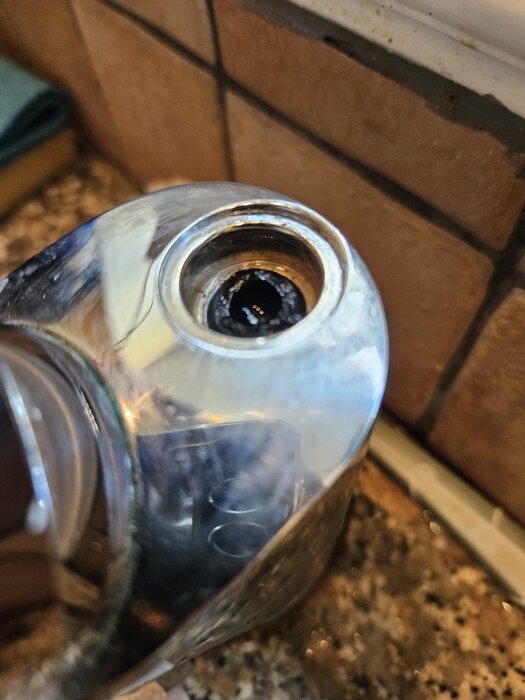 Närbild av en trasig köksblandare, där en plastadapter med gängor har gått av vid pipen.