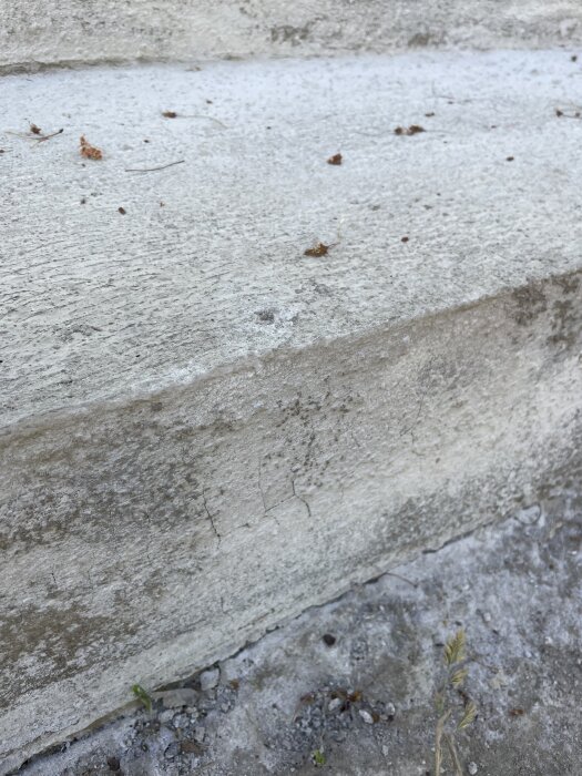 Bilden visar en utomhustrappa i betong med tydliga ytsprickor och ojämn yta. Det finns även kalkutfällning och färgskiftningar synliga.