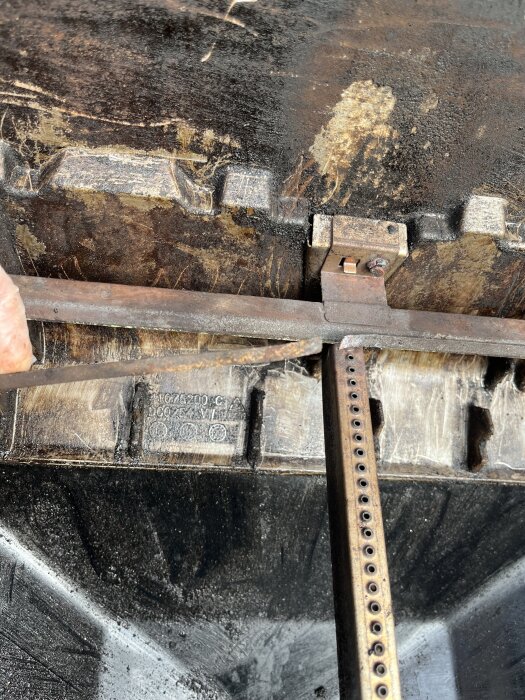 Närbild av en Weber Genesis 2-grill med fokus på ett brännarrör där en list har lossnat och brännarna är slitna.