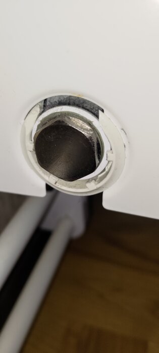 Närbild av en plastring och metallmutter på ett vattenelement från 2012. Ringen håller sidopanelen på plats och är delvis trasig.