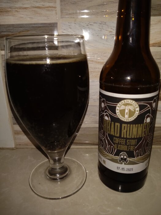 Flaska och glas med alkoholfri coffee stout Road Runner på ett marmorbord.