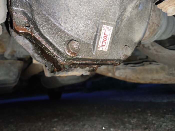 Läcker differential med oljedroppar och etikett med text "ONLY LSD OIL" på undersidan av en bil.