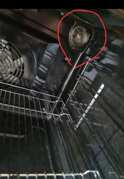 Ugnens insida med trasig lampglas täckt av ett skydd i höger hörn, markerat med röd cirkel.