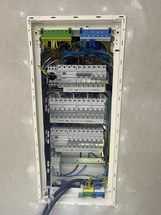 Elektrisk central monterad i väggen med flera säkringar och kablage.