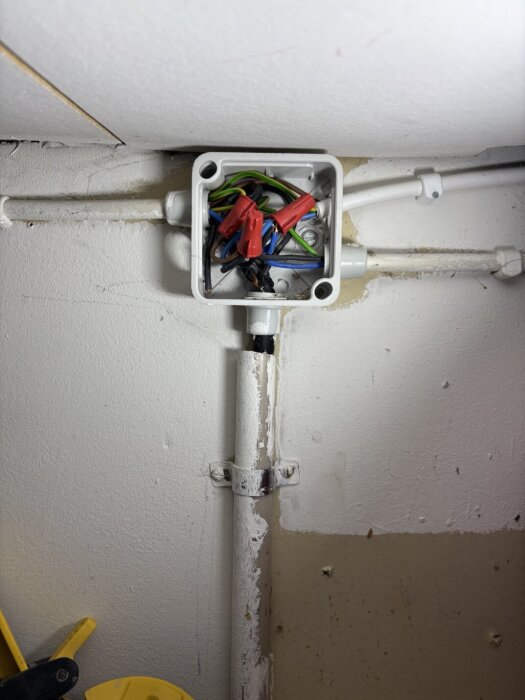 Elinstallationsdosa med öppet lock och flera elledningar i olika färger, fäst vid en vägg i ett 1,5-plans hus från 1983.
