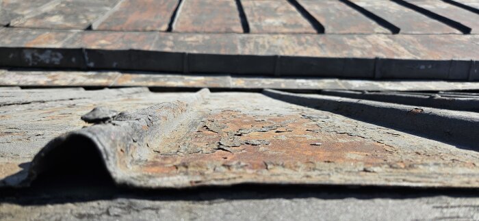 Korrosionsskadat falsat plåttak före målning, med tydliga tecken på rost och slitage.