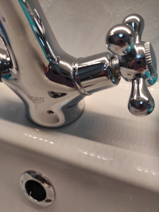 Kromkran av märket Noro monterad på en vit handfat.