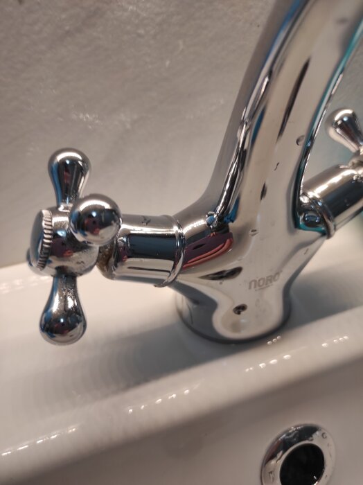 Kromad kökskran med dubbla vred mot vit bakgrund.