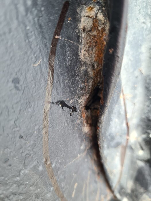 Närbild av ett tak med rost och ett potentiellt hål där vattenläcka kan uppstå. Skador syns på grund av tidigare blästring och målning.