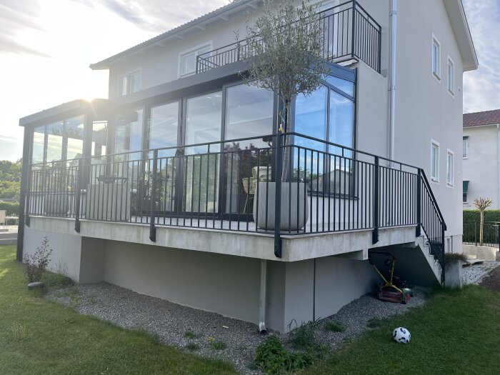 Modern glasad terrass med metallräcke och föreslagen terasskjol.panelen under är omålad med grus och trädgårdsutrustning under.
