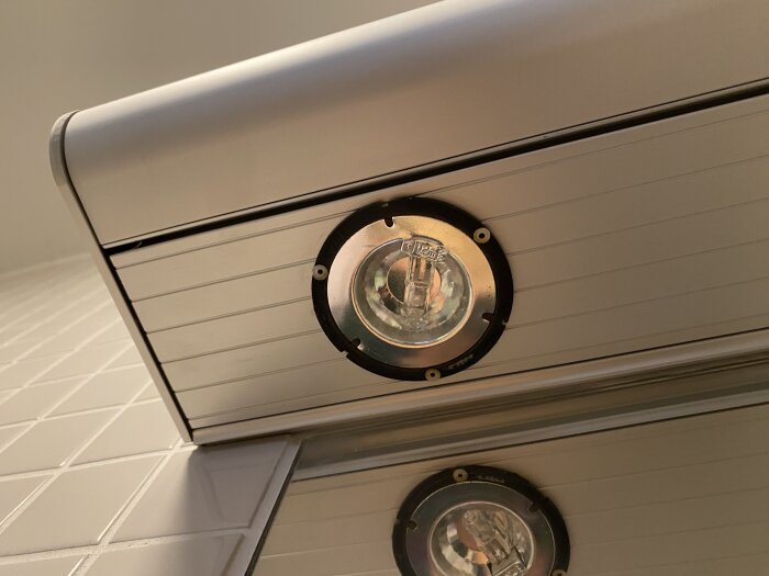 Belysningsramp med spotarmatur i badrum ovan spegel, svåråtkomliga monteringshål syns på sidan av armaturen.