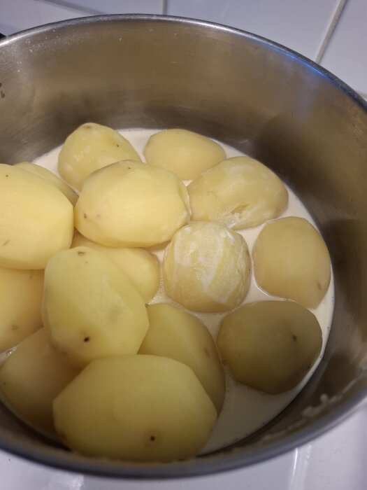 Kokta potatisar i en kastrull med grädde, förberett för att göra potatismos.