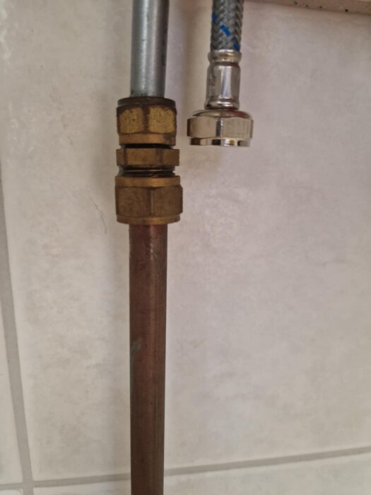 Rör och anslutning till blandare på kaklad vägg, visande behov av koppling eller skarv för installation.