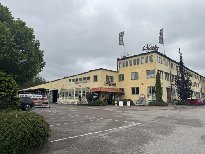 XL-byggbutik i liten svensk kommun med parkeringsplats och reklam för takmaterial.