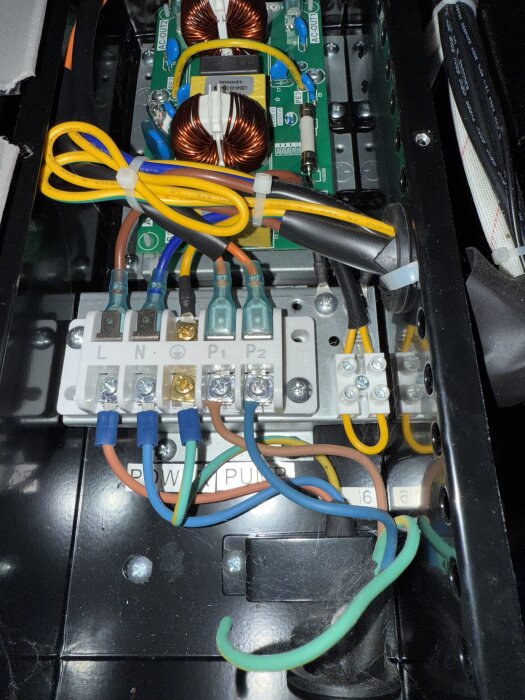 Elektrisk kopplingsbox med kablar, plintar och kretskort för poolpump. Två stora kopparspolar synliga.