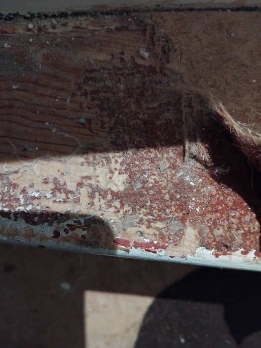 Röd fläckig yta på gammalt trappsteg med antydan av slitage i ett hus från 1945, angränsande till frågan om det kan vara asbest.