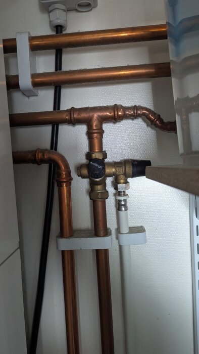 Kopparrör och ventiler i bergvärmeanläggning, inklusive en avstängningsventil.