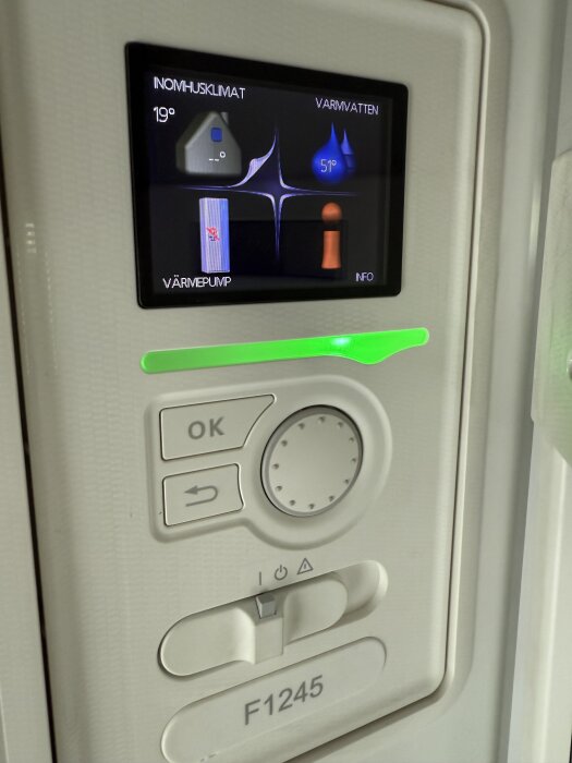 Display på värmepump med kontroller, visar inomhusklimat och vattentemperatur. Modellen är F1245 med "OK" och bakåtknapp.