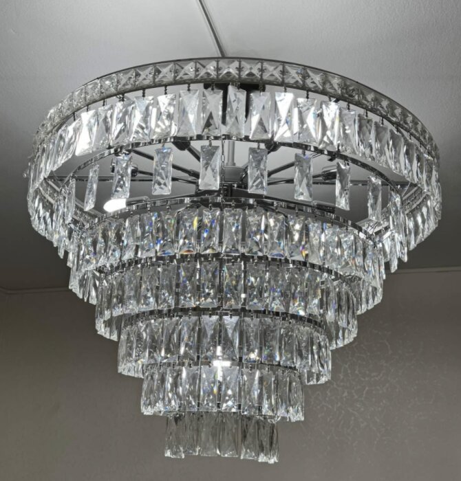 Kristallkrona med flera lager hängande kristaller, monterad i ett tak.