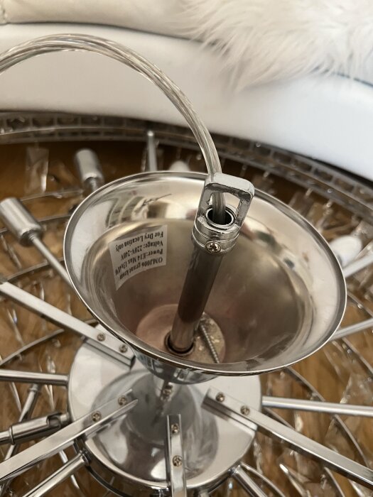 Kristallkrona liggande på golvet, med fokus på metallinfästning och upphängningskrok.