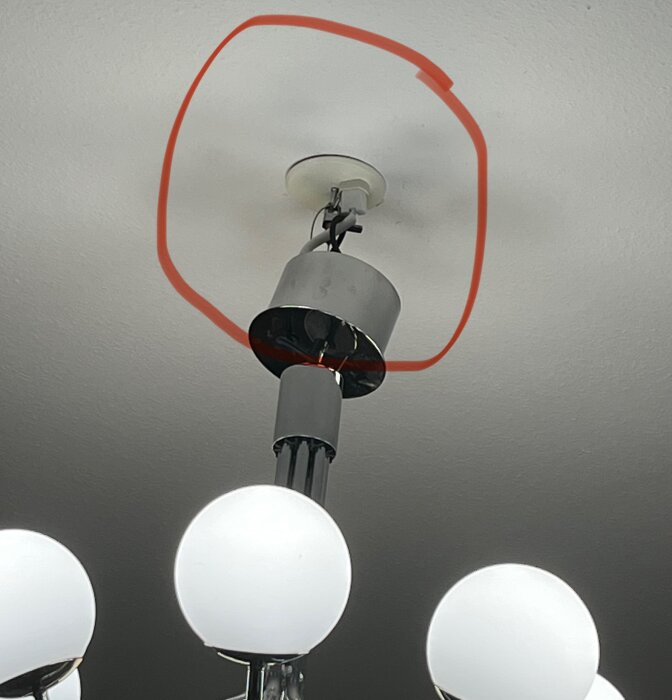 Lampa fäst vid tak, röd cirkel visar där den ska hänga. Fyra vita ljuskällor synliga på lampan.
