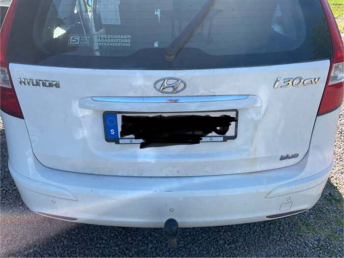 Vit bil med ojämn färg, rostskador behandlade och övermålade med vit sprayfärg, resultatet ser ut som en "målad teckning".