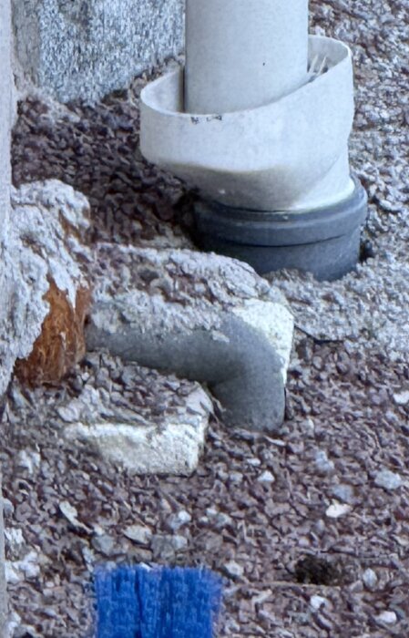 Isolerat rör utomhus går genom vägg på sutterängplan, omgiven av frigolit och puts, arbetar på ombyggnad av isoleringslåda.