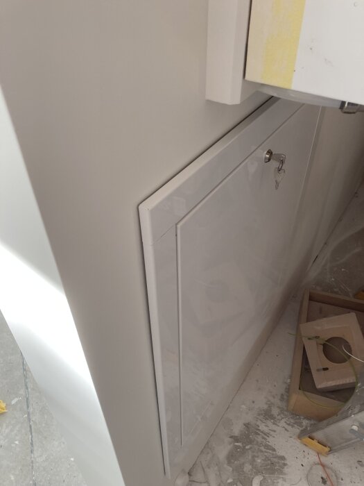 Skåp för golvvärme monterat jäms med gipsvägg, omgivningen visar spår av byggmaterial och verktyg.