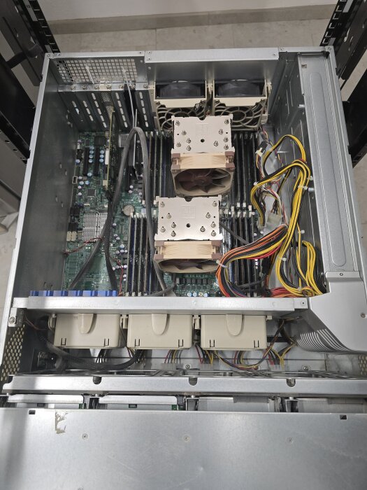 En serverkassett monterad i ett rack, med kylfläktar, moderkort och kabeldragningar synliga ovanifrån på en verkstadsgolv.