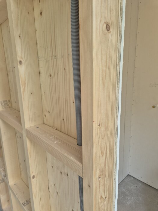 Väggkonstruktion med träreglar, våtrumsgips och synlig elinstallation i en bastubyggnation.