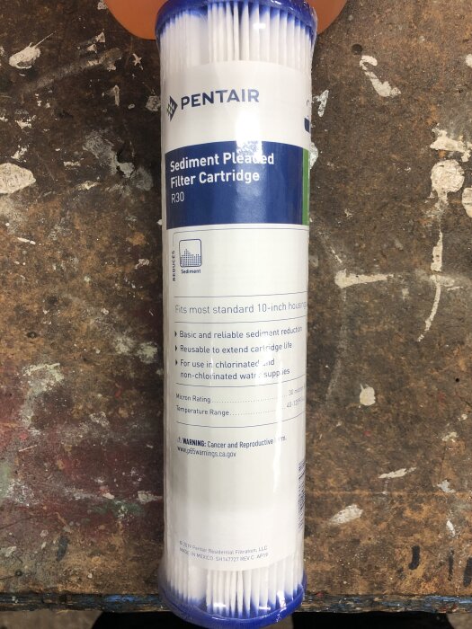 Patronfilter för sediment från Pentair, typ R30, placerat på en arbetsbänk. Används för vattenfiltrering, passar 10-tums standardhus.