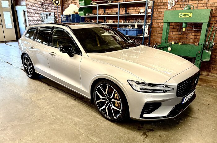 Silverfärgad bil i garage efter sommarvaxning, odelad baklucka, sportiga fälgar, synlig nummerplåt.