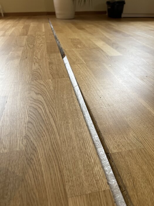 Närbild på ett parkettgolv med en synlig fog där en tröskel mellan vardagsrum och kök ska installeras.