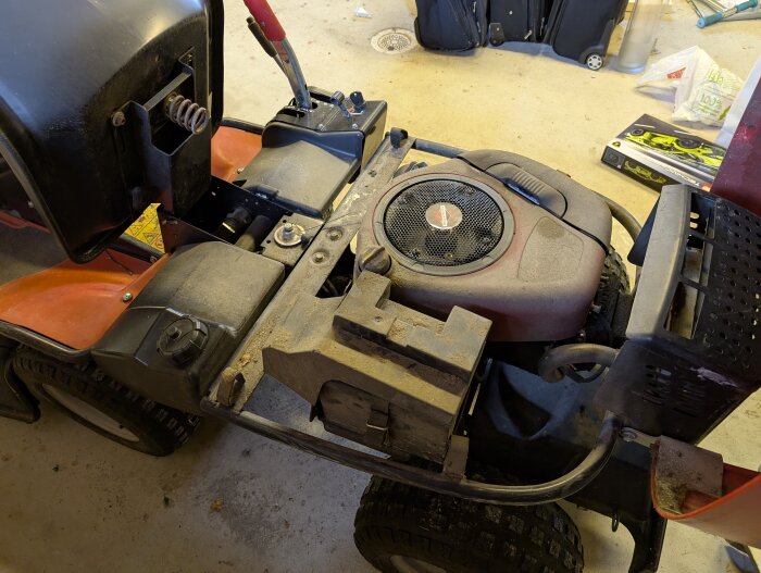 Åkgräsklippare Jonsered FR2113A parkerad i garage, med synlig motor och chassi, undersöker frågor om kopplingen.