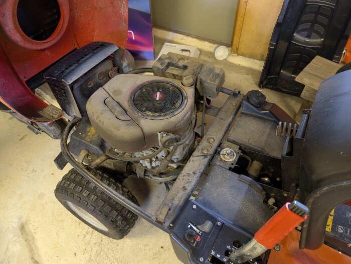 Närbild av insidan på en Jonsered FR2113A åkgräsklippare i ett garage, med fokus på motorn och dess komponenter.