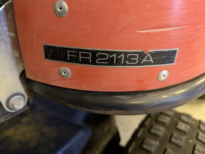 Röd Jonsered FR2113A med namnskylt och synlig däckdel, slirande koppling problem beskrivs i texten.