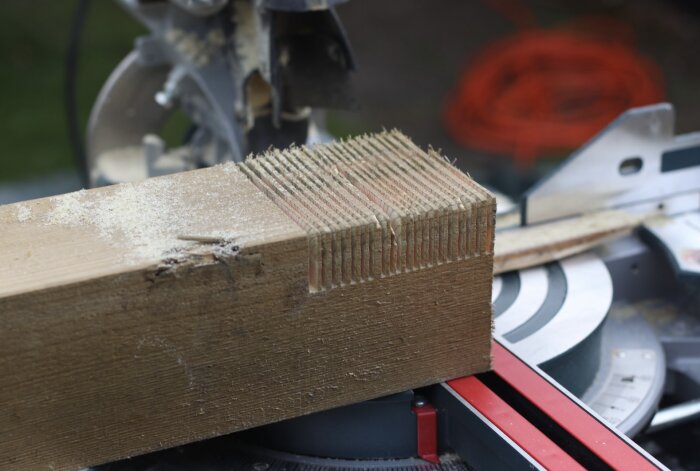 Närbild av ett kapat trästycke på en såg med snitt som inte går hela vägen igenom, vilket skapar en ojämn yta i slutet.