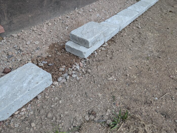 Betongstenar placerade på mark utan fundament, med ojämn markyta och synlig jord runt omkring.