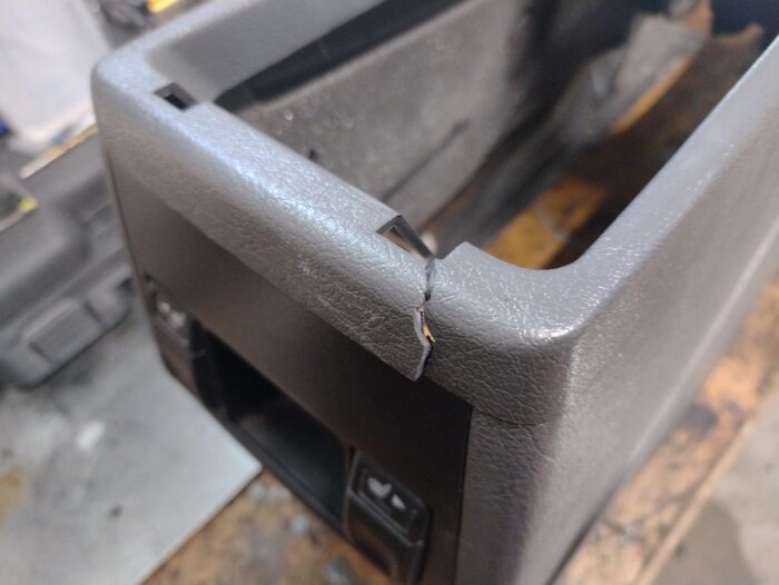 Sprucken centerkonsol från en Volvo 850, visar en stor spricka i plasten som behöver lagas med epoxi för att förstärkas och repareras.