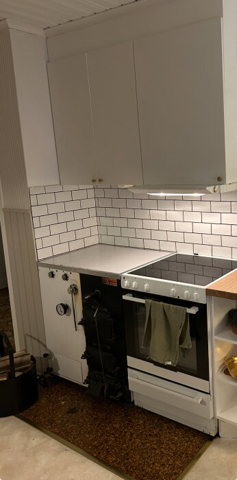 Brun rektangulär betongplatta framför vedpanna och spis i kök, del av stuga.