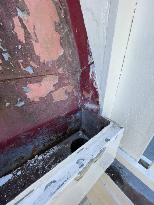 Rostiga och delvis avflagnade hängrännor i plåt, med röd och vit färg, redo för rengöring och ommålning med Alcro Pallad färg.