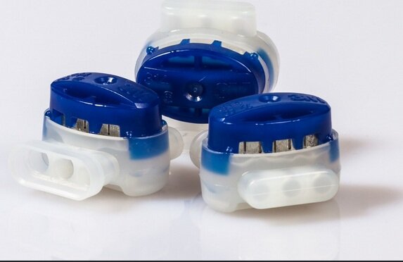 Tre elektriska kabelkopplingar med blå plastlock, liggande på en vit yta.