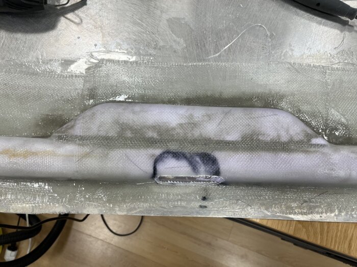 Plastad ficka för låskista i dörrkonstruktion, där epoxi och glasfiber förstärker en balk, redo för montering av lås- och gångjärnsfästen.