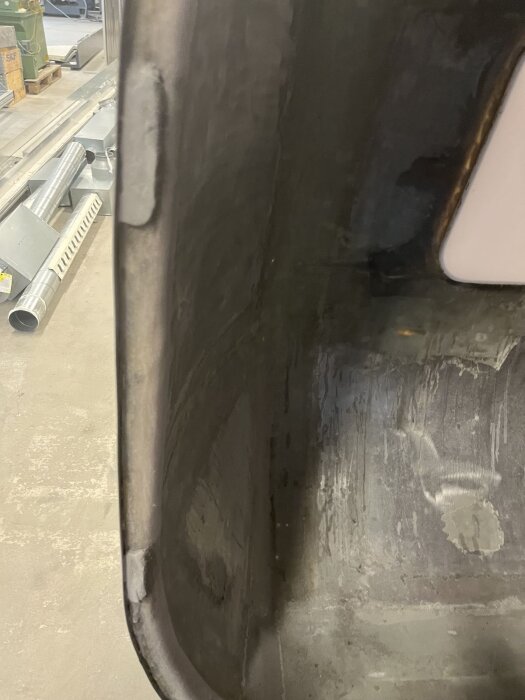 Interiör av förstärkt dörr med monterade aluminiumprofiler och plastfickor, synliga epoxi-reparationer och byggmaterial i bakgrunden.