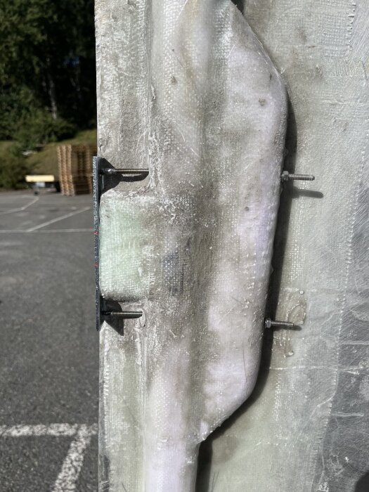 Bild av förstärkta balkar med monterade gångjärn i en dörrkonstruktion under utomhusförhållanden.
