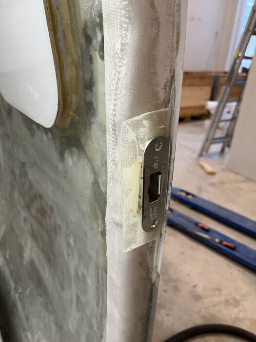Närbild av en dörrkant under montering med ett låshus insänkt i dörrens förstärkta struktur av glasfiber och aluminium.
